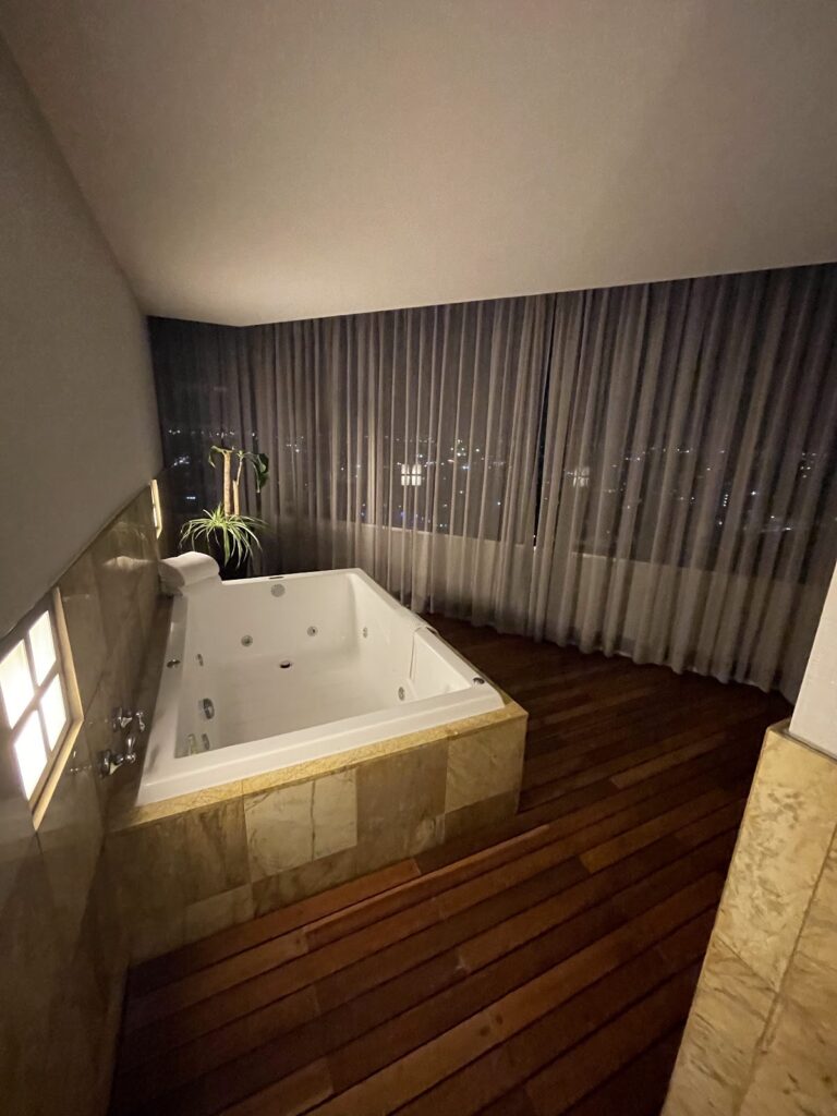 Jacuzzi tub with night city views in suite