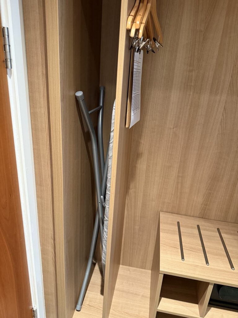 Wardrobe with ironing board and hangers in guest room