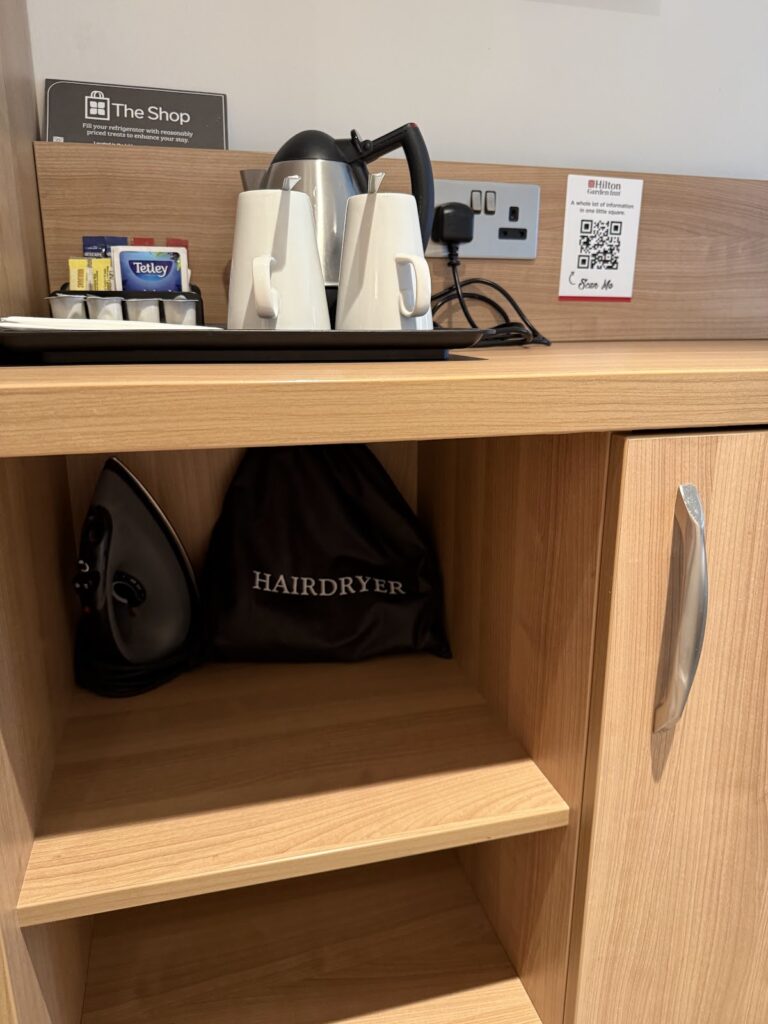 Kettle, iron, and hairdryer in hotel room cupboard
