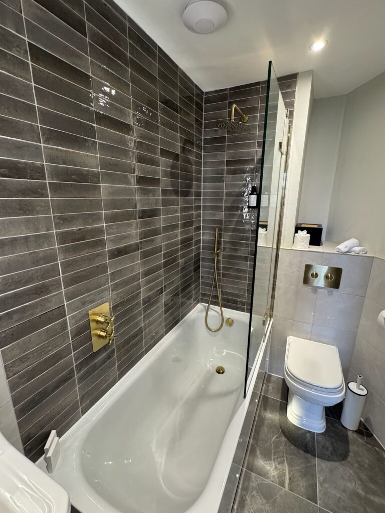 Modern bathroom with dark tiles and brass fittings
