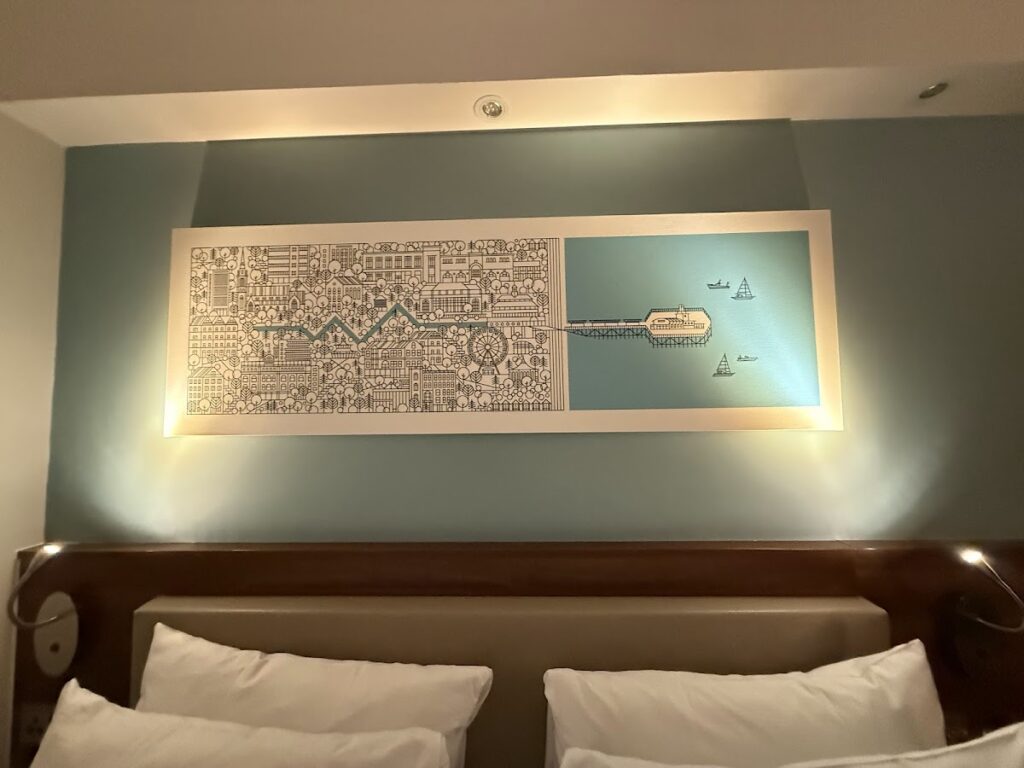 Bournemouth pier artwork above bed at Hampton by Hilton