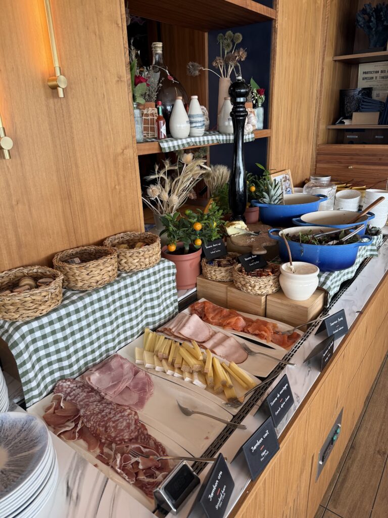 Breakfast buffet with meats, cheeses, bread, and hot dishes