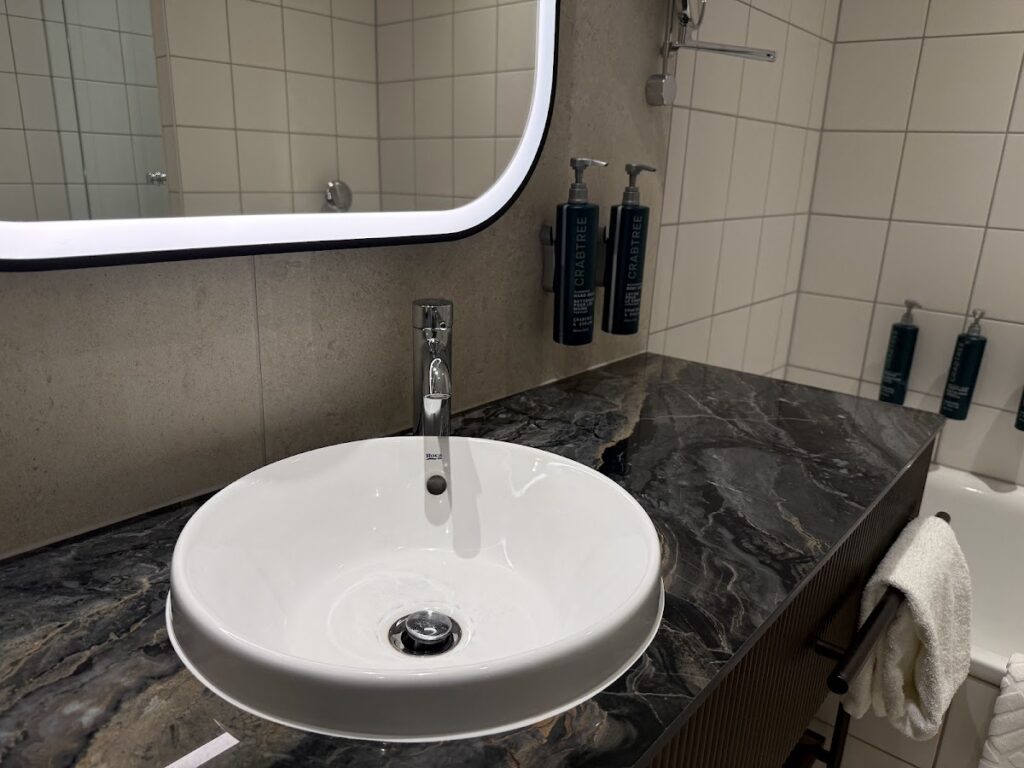 Bathroom sink and illuminated mirror at Hilton Cologne