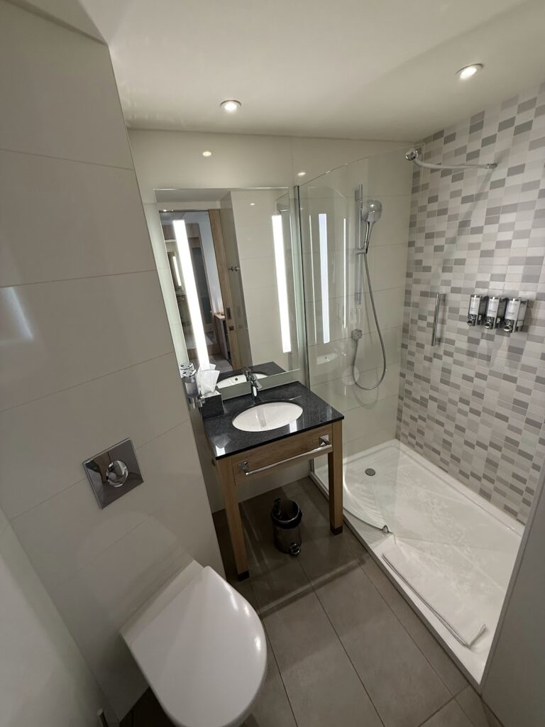 Compact bathroom with walk-in shower, sink, and toilet
