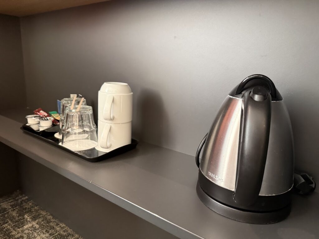 In-room kettle and tea tray on grey shelf