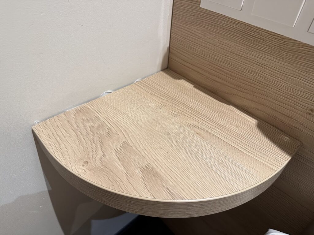 Small wooden bedside shelf with scuffed wall corner