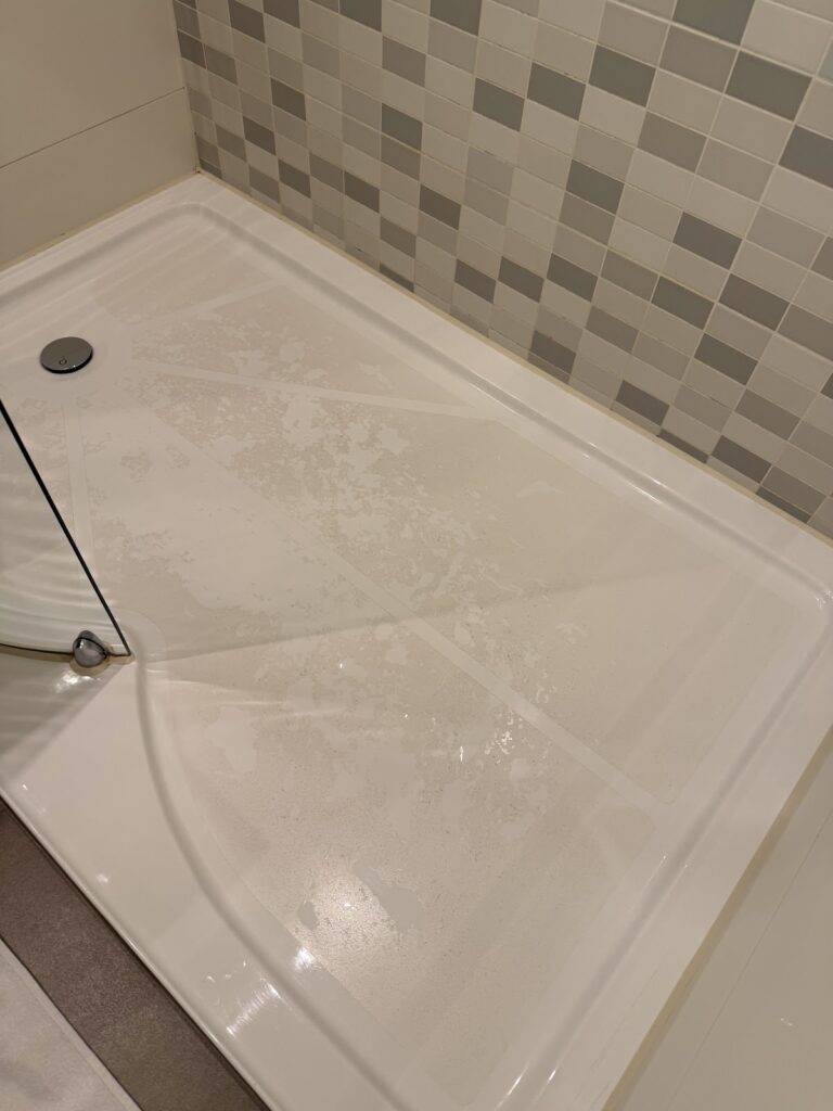 Shower tray with visible staining and tiled wall