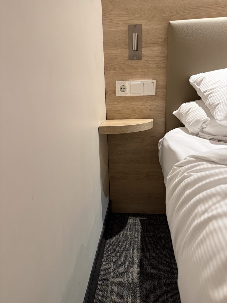 Bedside shelf, sockets and wall light beside bed