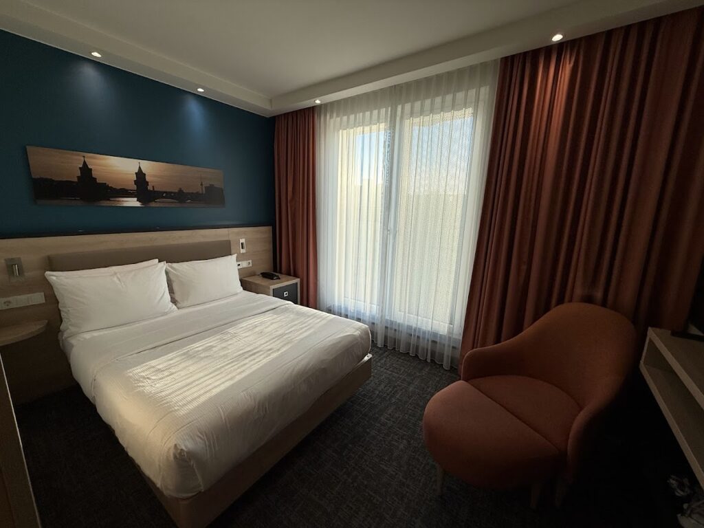 Double bed and orange chair in Hampton Berlin Alexanderplatz room