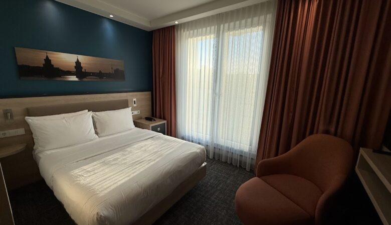Double bed and orange chair in Hampton Berlin Alexanderplatz room