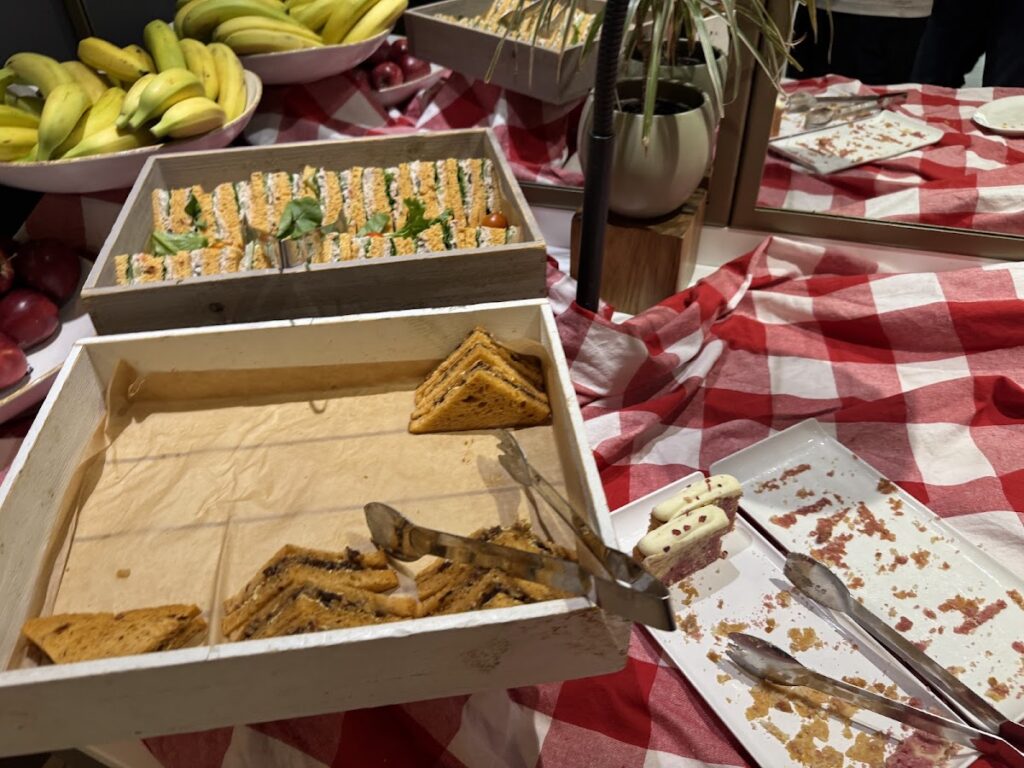 Untidy buffet trays with sandwiches, sushi and fruit