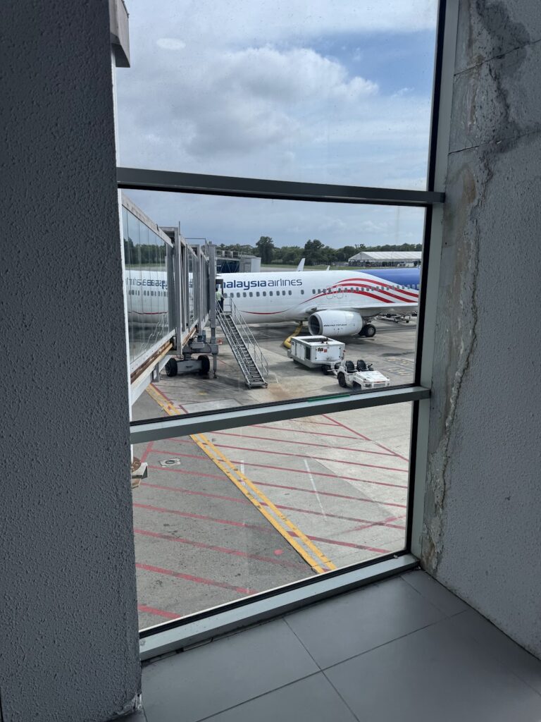 Malaysia Airlines 737 at gate viewed through terminal window