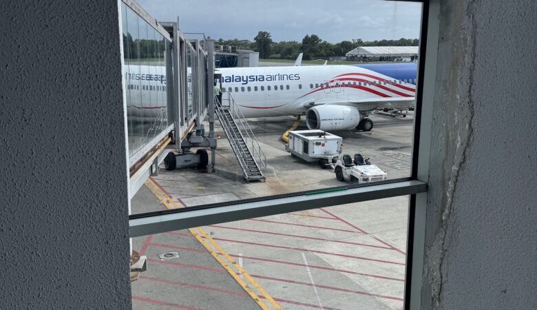 Malaysia Airlines 737 at gate viewed through terminal window