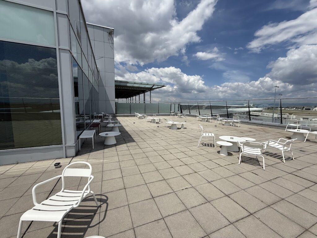 Outdoor terrace with white chairs overlooking Sofia Airport apron
