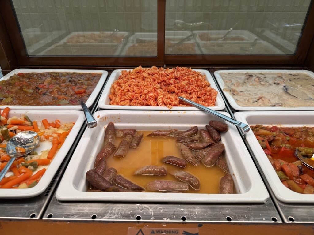 Hot buffet trays with pasta, sausages and stew