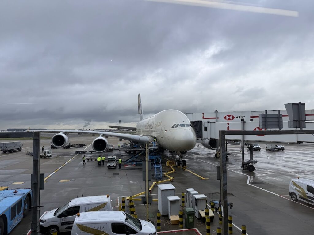 Etihad A380 parked at Heathrow gate under cloudy sky