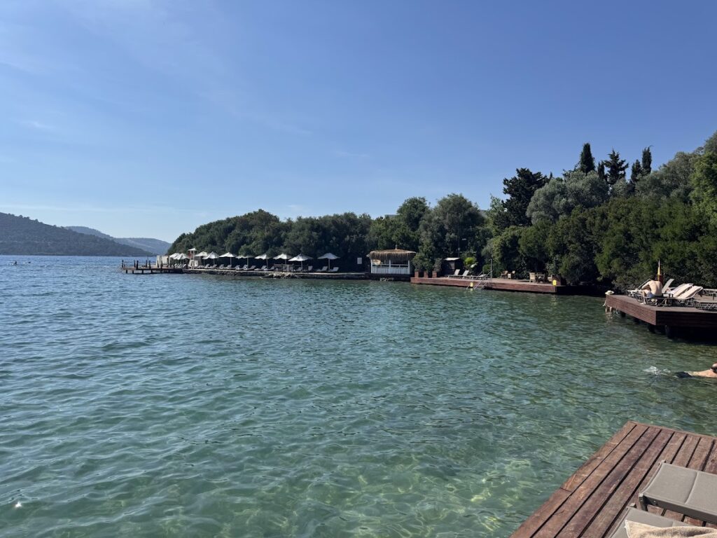 Turquoise Aegean Sea with beachfront loungers and trees