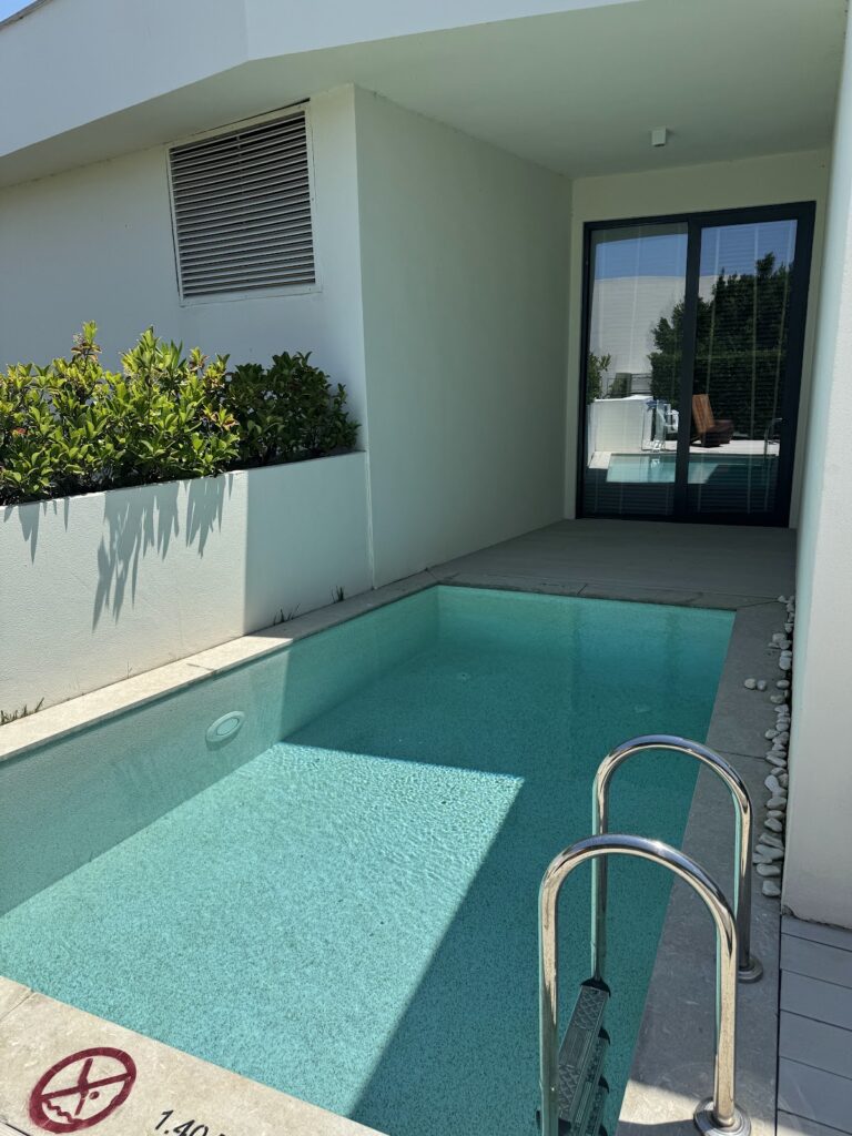 Private turquoise plunge pool with modern white building and glass