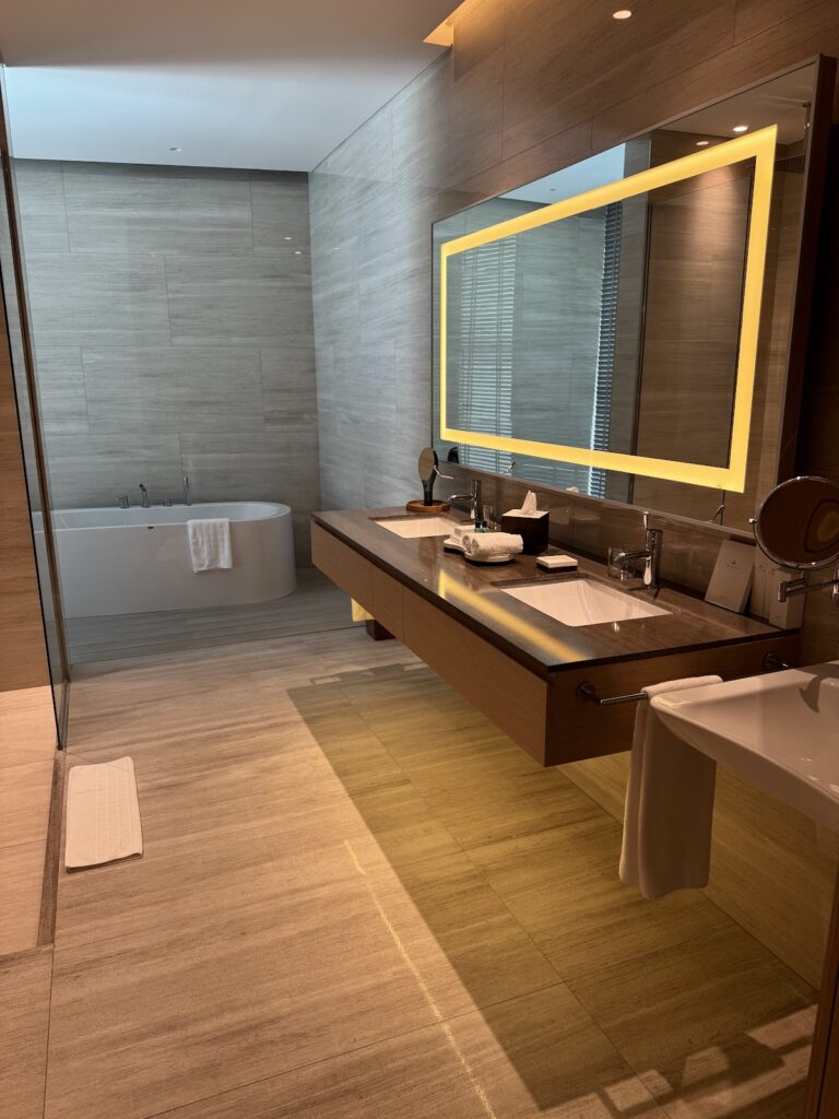 Luxury bathroom with illuminated mirror, wooden finishes, and circular soaking