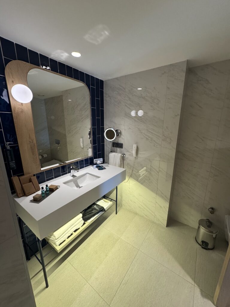 Modern bathroom with marble, wooden mirror frame, and rainfall shower