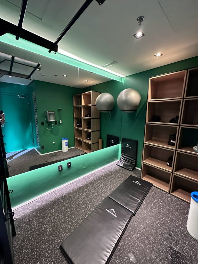 Modern hotel gym with green walls and mirrors