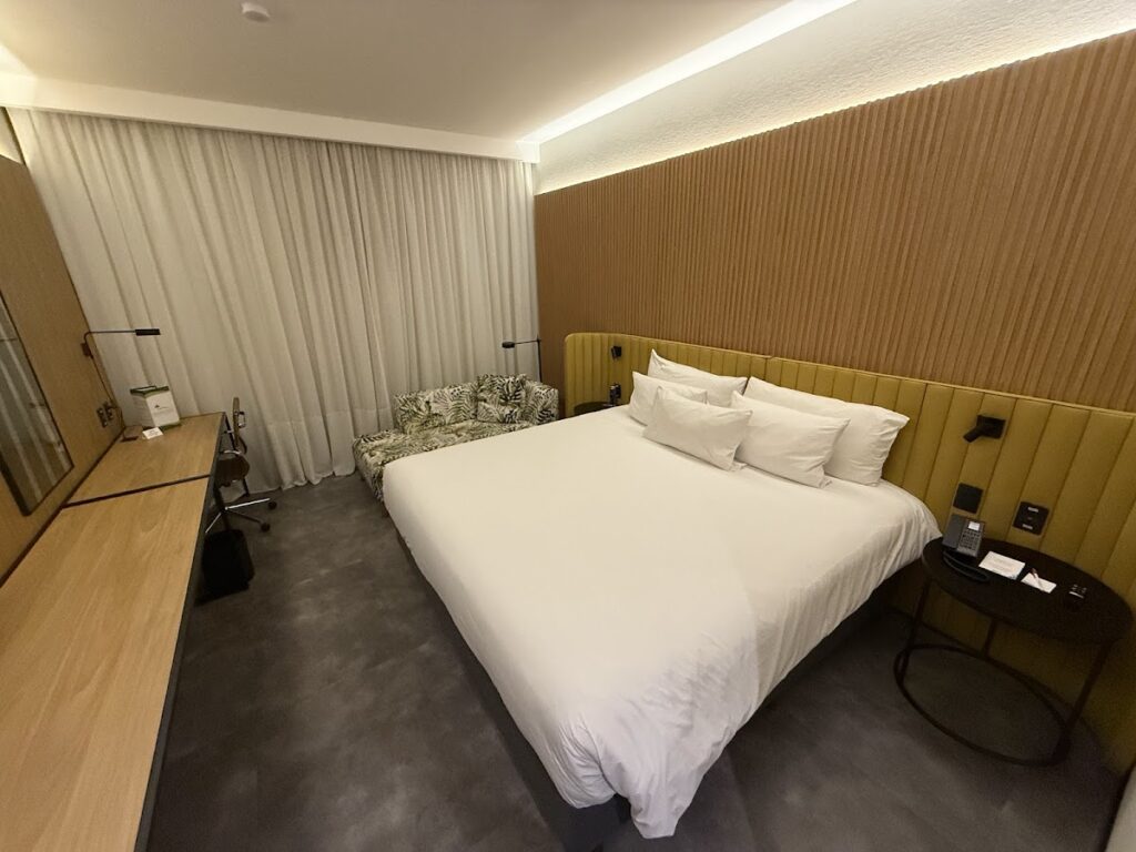 Hilton Garden Inn Rebouças king bed with yellow headboard.