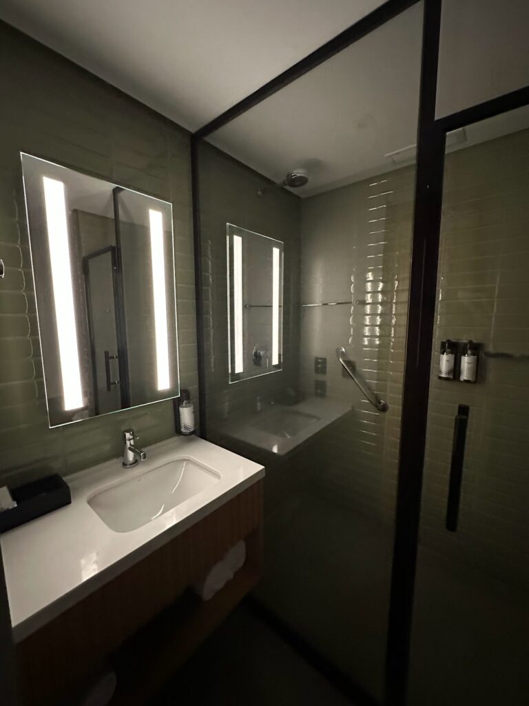Modern bathroom with lit mirror, shower, green tile