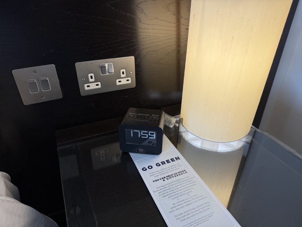 Bedside control panel with digital clock and sustainability reminder