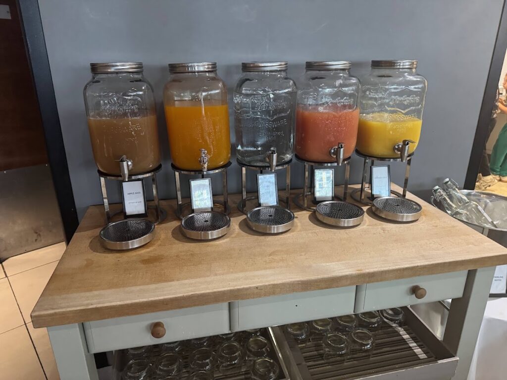 Five beverage dispensers with juices and water at hotel breakfast