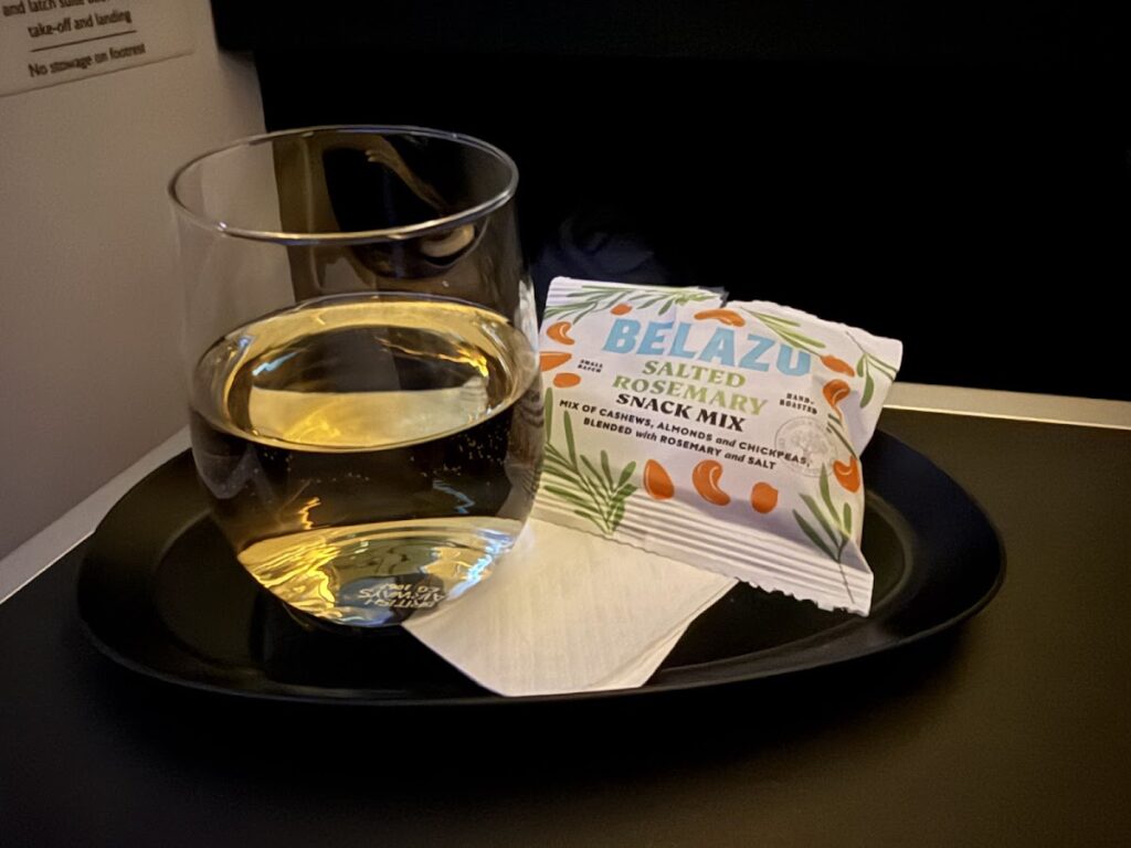 White wine and salted snack mix on tray table