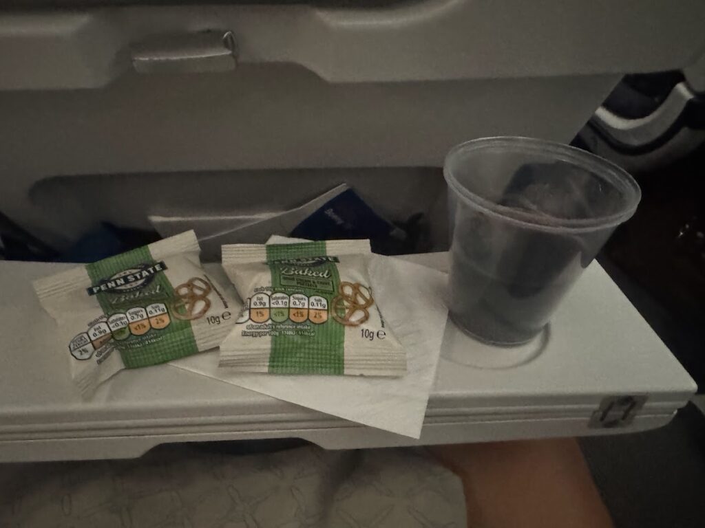 Snack service with pretzels and water on airplane tray
