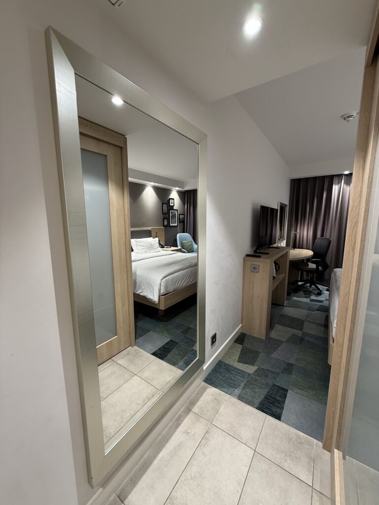 Modern bedroom viewed through doorway with ensuite bathroom entry