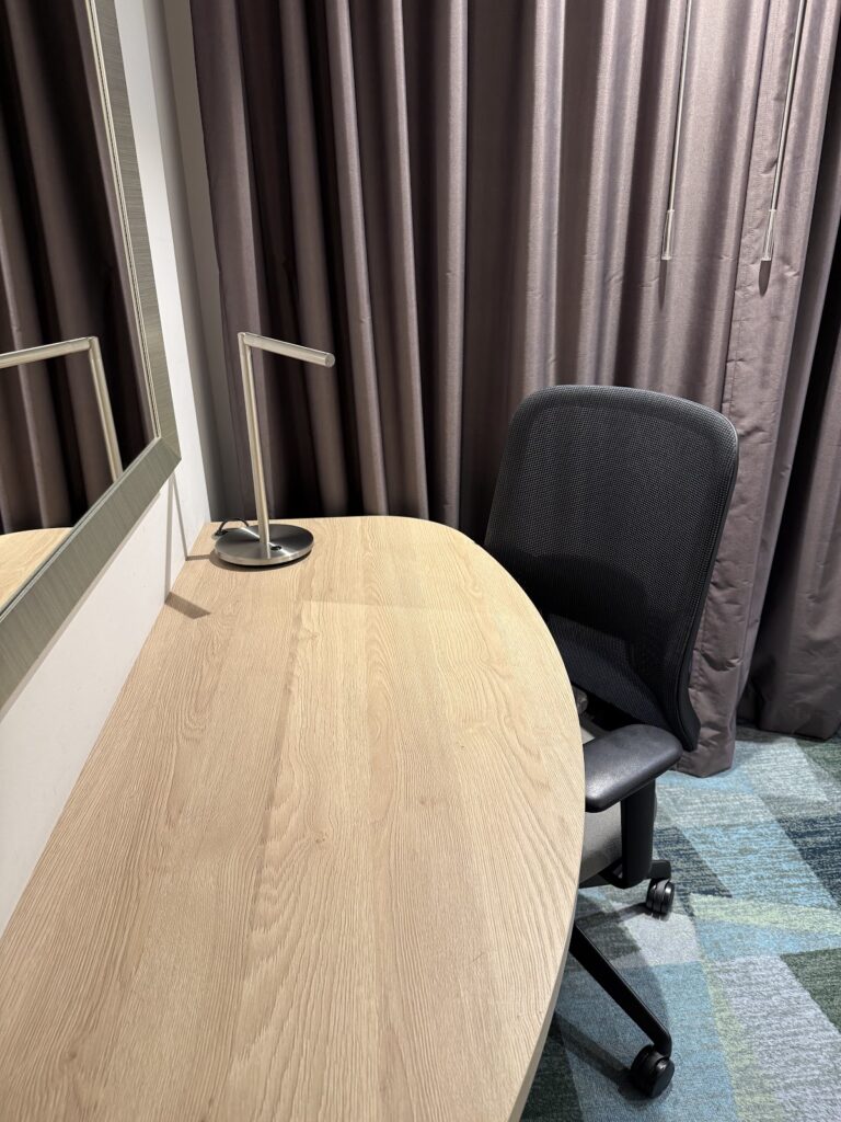 Guest room desk with chair, mirror, and heavy drapes