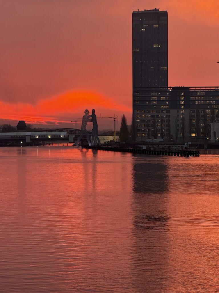 East Side Gallery Berlin sunset with Molecule Man sculpture