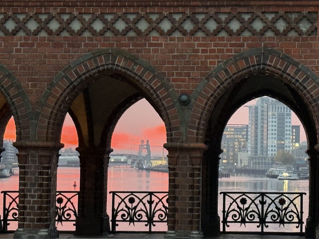 Scenic riverside view through red brick archways at sunset Berlin