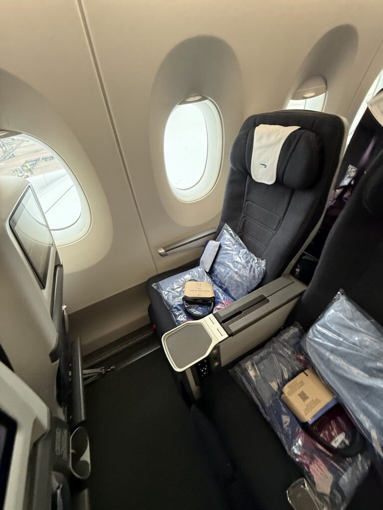 BA premium economy seat with window, pillows, and amenities