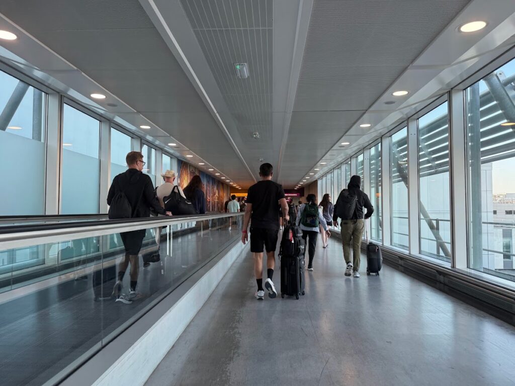 Modern airport corridor with floor-to-ceiling windows and travelers
