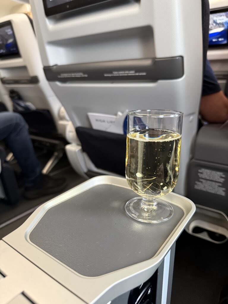 Champagne glass on grey tray table in BA premium economy