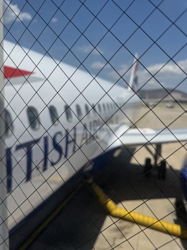 British Airways aircraft fuselage through security fence mesh